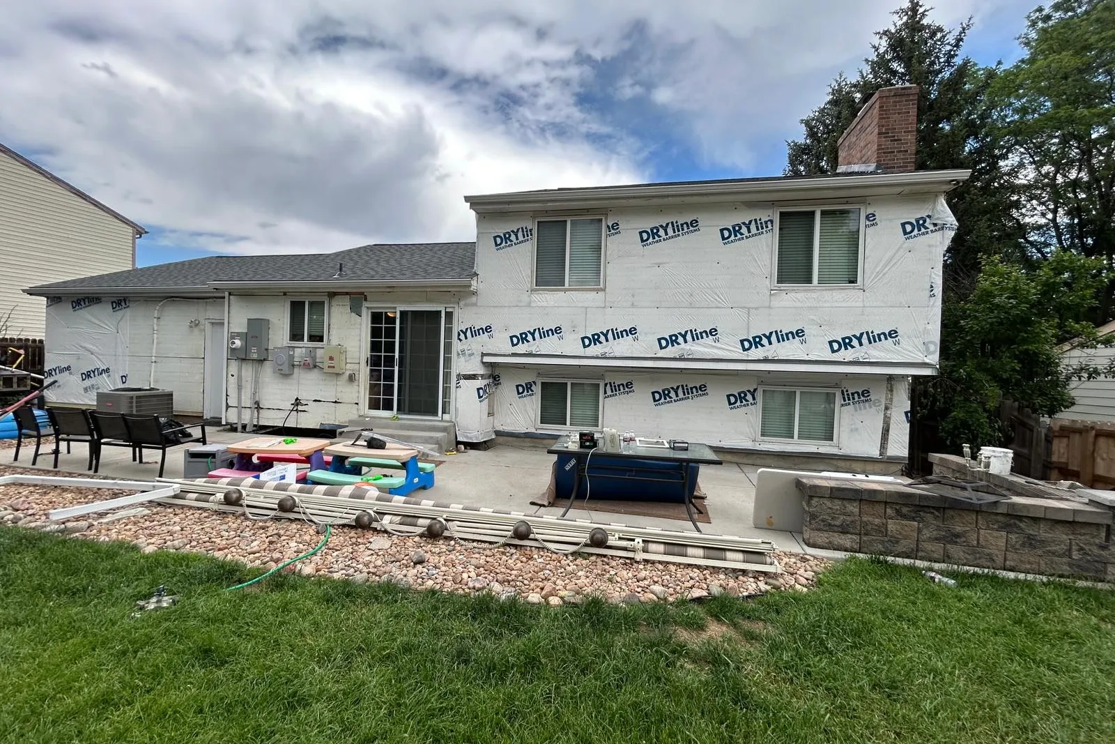 A Colorado home wrapped in a code-listed weather-resistive barrier with new windows set, photographed before the siding goes on — the moisture-management stage of a Western Edge Exteriors re-side.